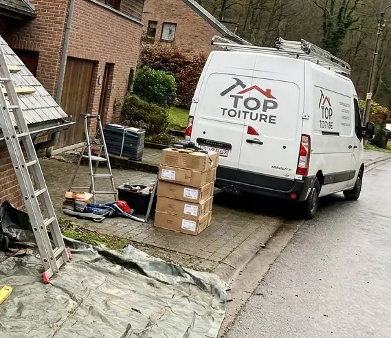 Camionnette Top Toiture, cartons de matériaux et échelle au pied d'une maison, bâche au sol