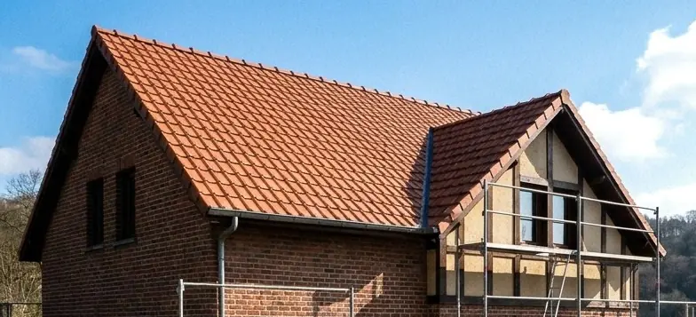 Toiture en pannes de terre cuite sur une maison en brique à colombages